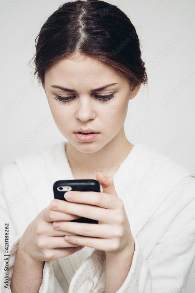 woman looking at mobile phone in her hands and white clothes light background woman looking at mobile phone in her hands and white clothes light background
