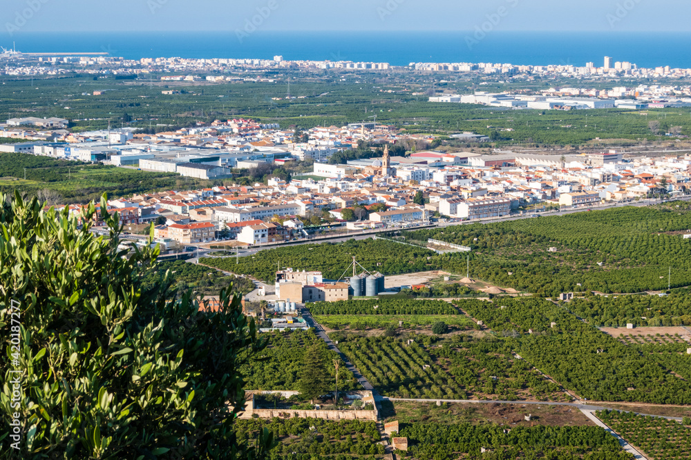 Aerial view of L'alquería de la Comtessa in Valencia (Spain), surrounded by orange groves, and with the Mediterranean Sea in the background.