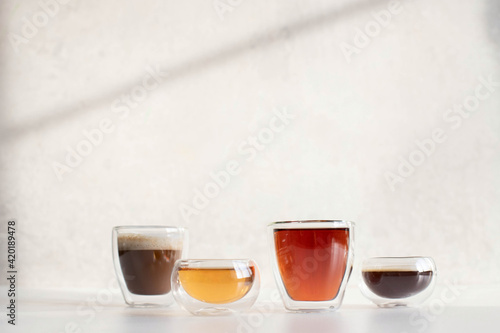 Soft drinks in double-walled glasses. Taken in harsh sunlight on a gray background