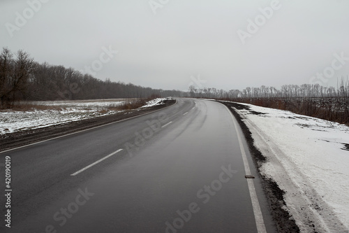 Wet road in winter among muddy spring snow