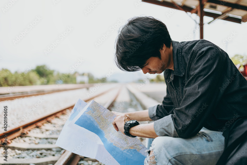 young man looking at him watch while waiting for the train at the railway station. Travel transport concept. young man looking at him watch while waiting for the train at the railway station. Travel transport concept.
