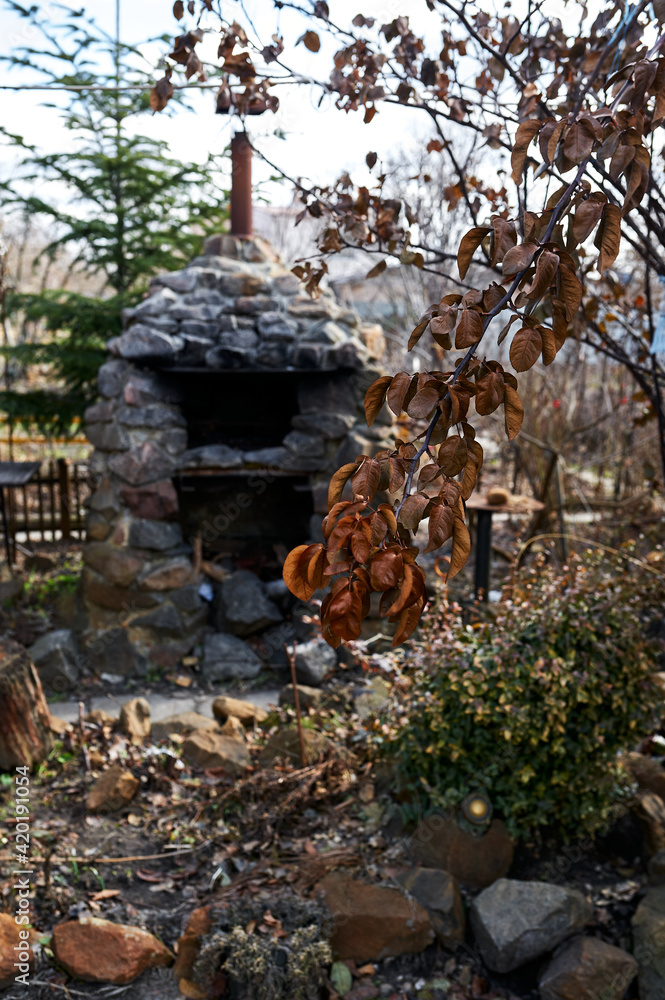 Obraz premium outdoor stone fireplace at their summer cottage against the background of a rose branch