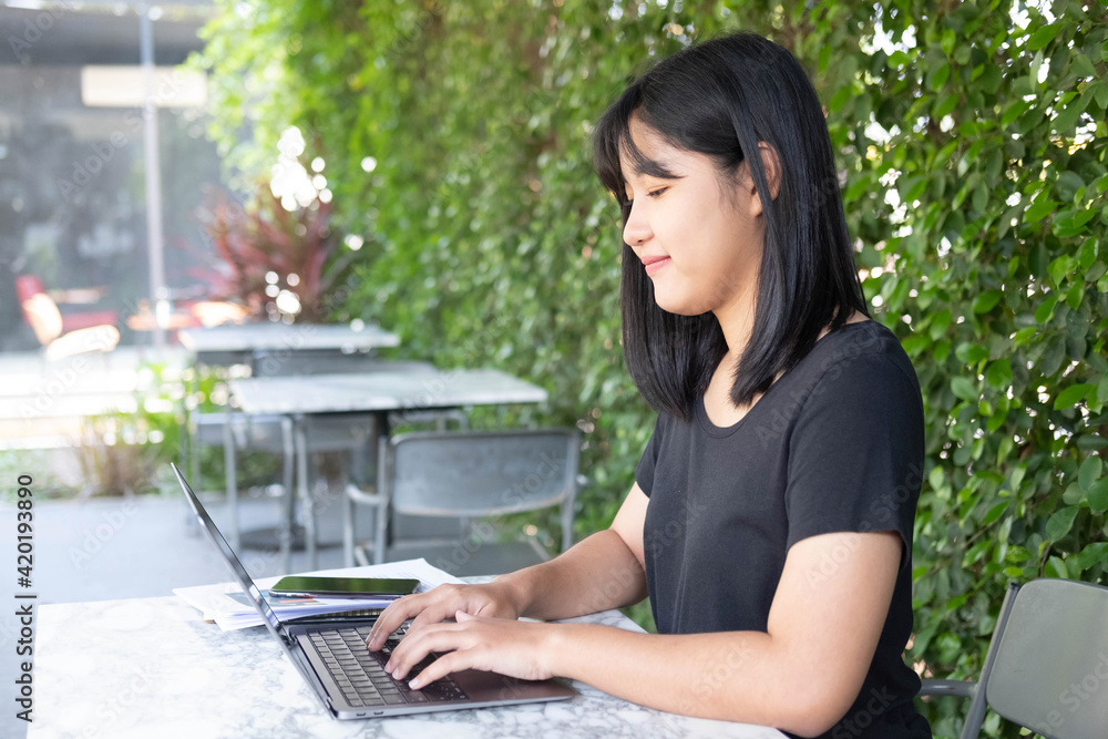 Young Asian woman freelance is working with laptop at coffee shop.
