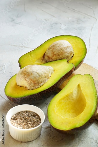 Sliced Avocado or Alpukat and a bowl of chia seed in textured-white background
