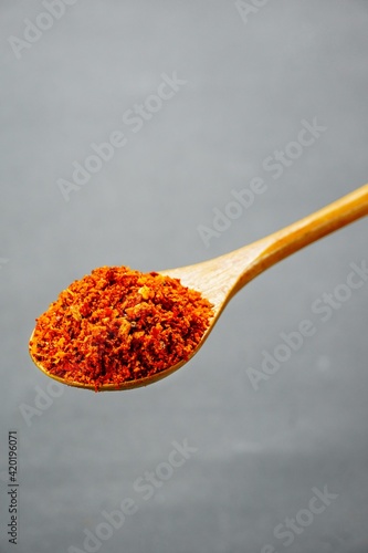 Selected focus of a spoon of chili flakes in isolated gray background