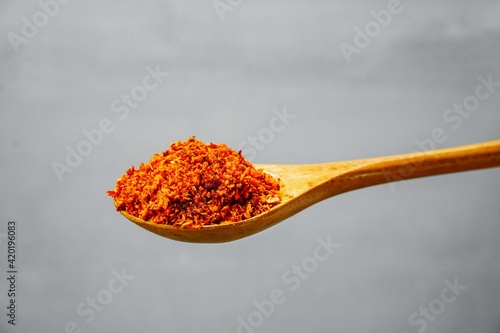 Selected focus of a spoon of chili flakes in isolated gray background