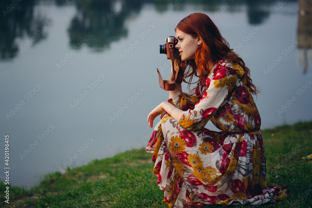 Obraz premium red-haired woman with a camera in nature near the lake