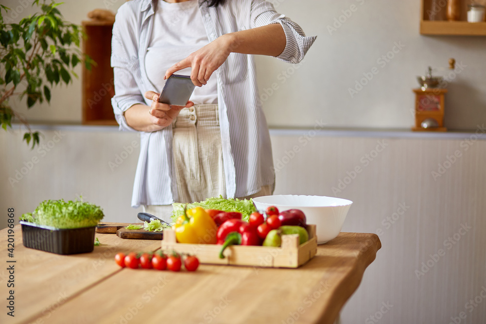 Woman taking photo of healthy salad with smartphone for her blog on kitchen at home, Food blogger concept, healthy lifestyle. Woman taking photo of healthy salad with smartphone for her blog on kitchen at home, Food blogger concept, healthy lifestyle.