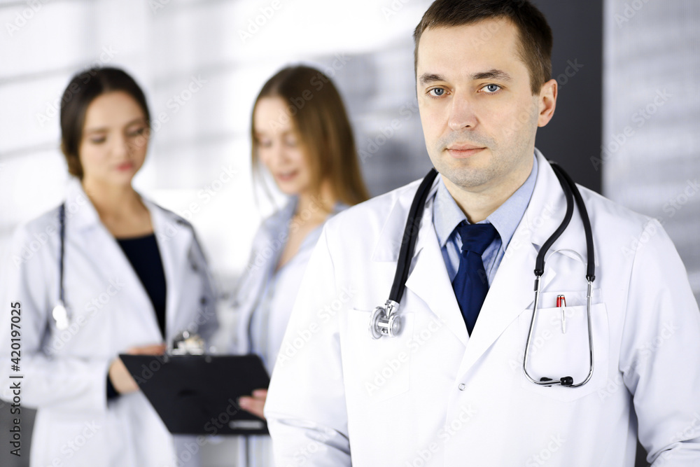 Professional middle aged doctor with a stethoscope at work with colleagues in a clinic. Perfect medical service in a hospital. Medicine and healthcare concept Professional middle aged doctor with a stethoscope at work with colleagues in a clinic. Perfect medical service in a hospital. Medicine and healthcare concept