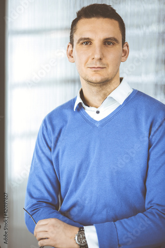 Friendly adult businessman in blue sweater. Business headshot or portrait in office