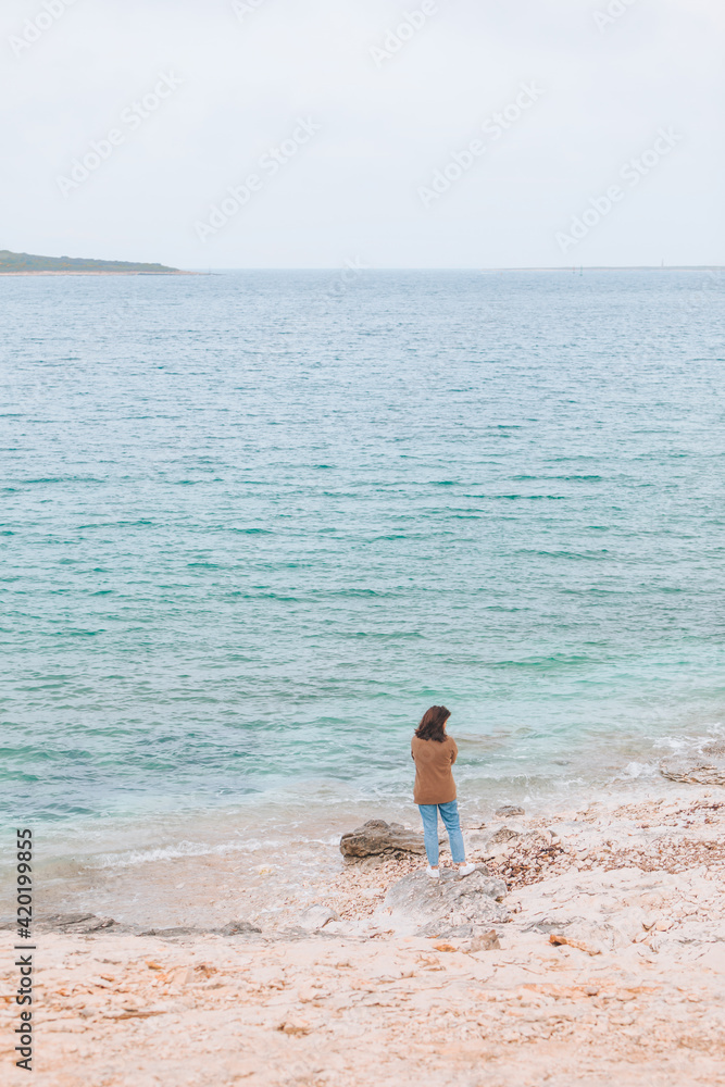 young woman rear view standing at windy sea beach young woman rear view standing at windy sea beach