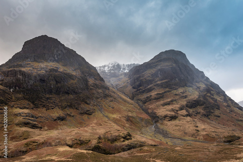 Majestic moody landscape image of Three Sisters in Glencoe in Scottish Highlands on a wet Winter day wit high water running down mountains photo