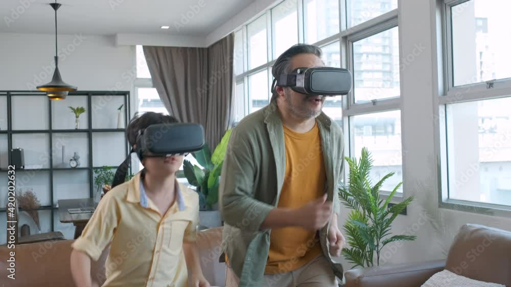 Asian father and son playing a game using VR Headsets. Asian father and son playing a game using VR Headsets.