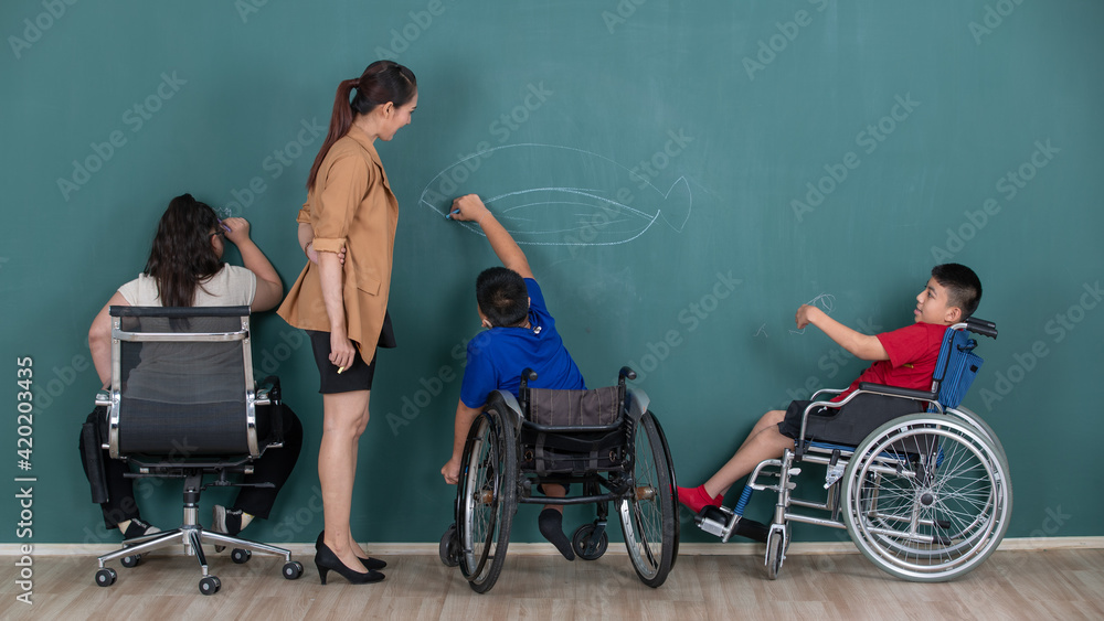 Group of special students in classroom, a down syndrome girl, two handicapped boys and cute Asian teacher drawing and painting on black board Group of special students in classroom, a down syndrome girl, two handicapped boys and cute Asian teacher drawing and painting on black board