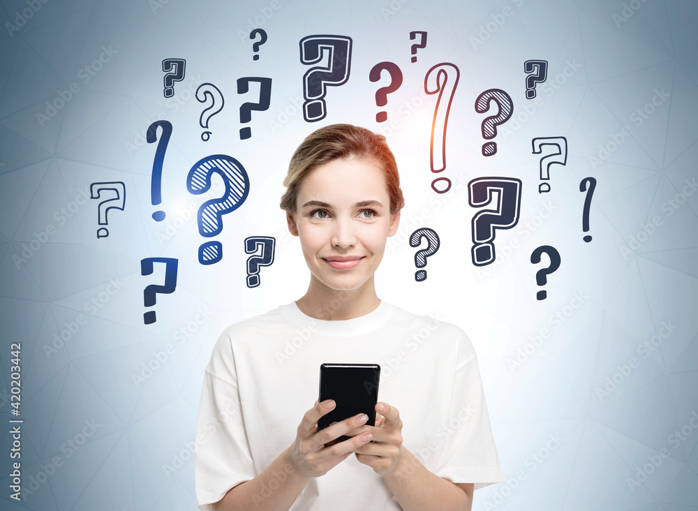 Young smiling girl in white t-shirt holding a smart phone and dreaming about future career opportunities. Question marks drawn on wall behind. Concept of searching for an answer. Young smiling girl in white t-shirt holding a smart phone and dreaming about future career opportunities. Question marks drawn on wall behind. Concept of searching for an answer.
