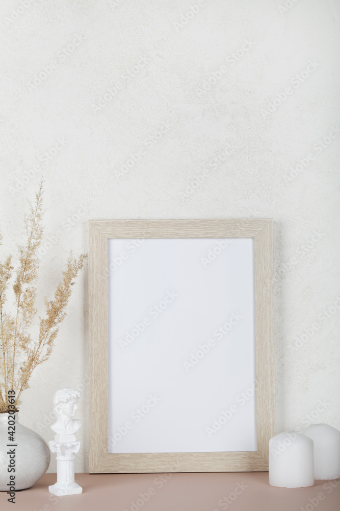 Portrait empty wooden frame mockup, dried pampas grass, small statue and candles on white background, interior, home design. Art concept. copy space. 