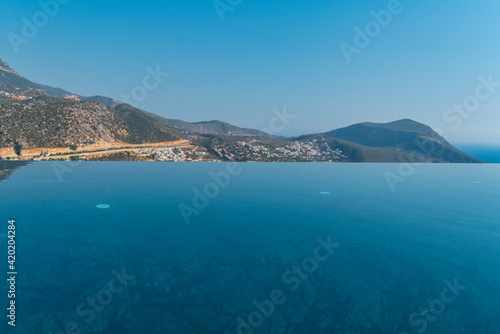 Infinity swimming pool with sea and ocean view on blue sky background © isilterzioglu