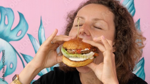 Very hungry young woman eats her vegan burger with great pleasure and joy
