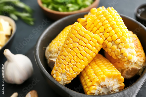 Obraz na płótnie Frying pan with tasty baked corn cobs on dark background