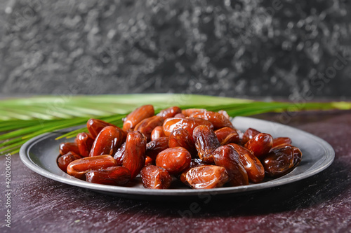 Plate with sweet dried dates on dark background