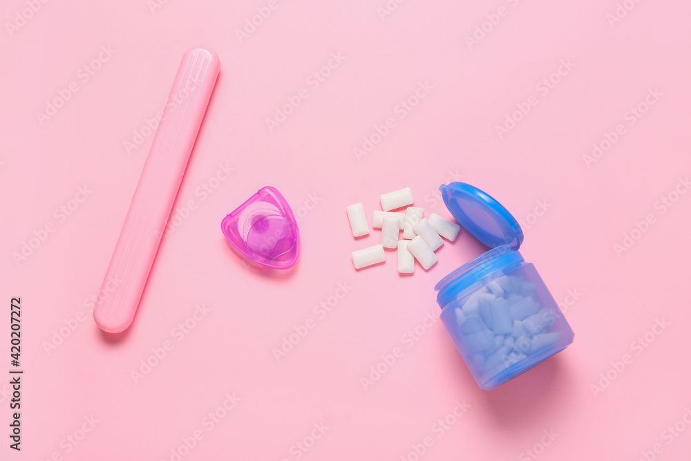 Tasty chewing gums with supplies for dental hygiene on color background