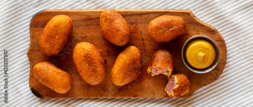 Homemade Mini Corn Dogs on a rustic wooden board, top view. Flat lay, overhead, from above. photo