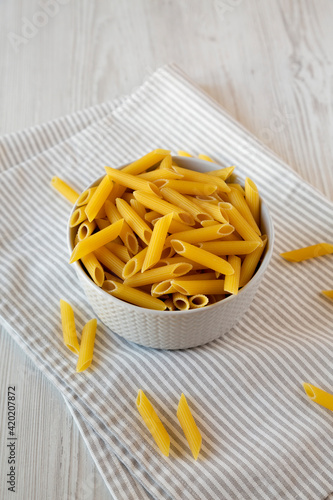 Uncooked Organic Penne Pasta in a Bowl, side view.