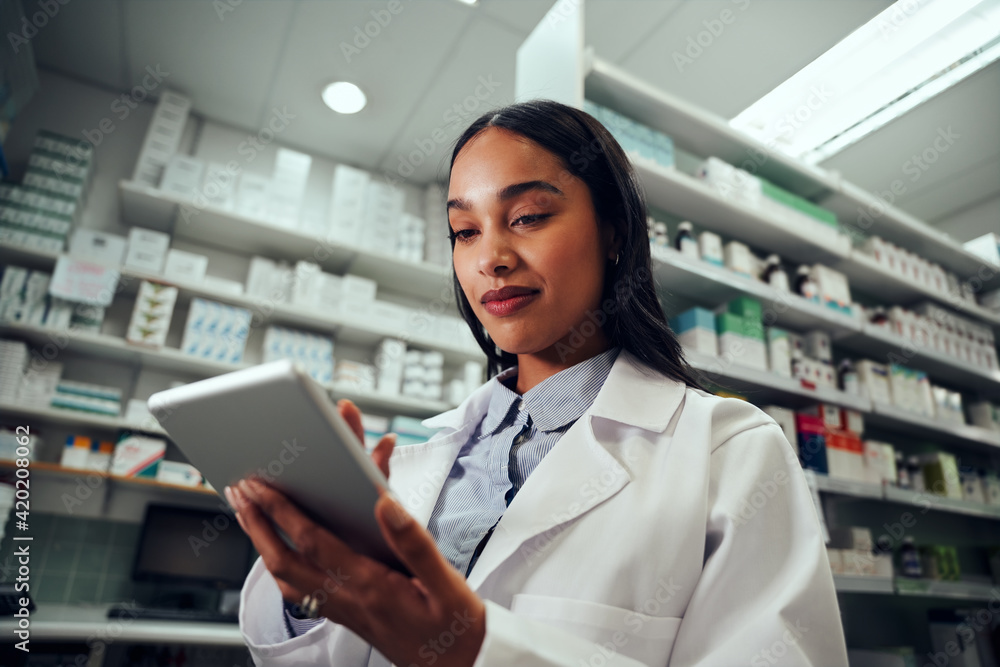Low angle view of woman pharmacist wearing labcoat uniform using digital tablet