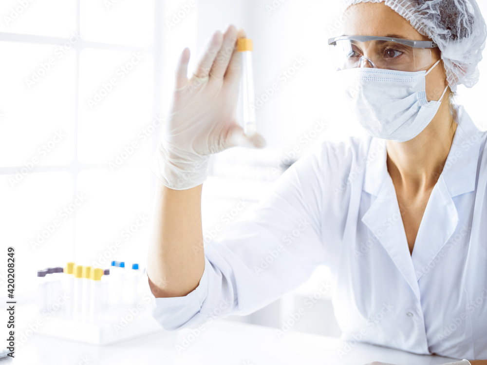 Professional female scientist in protective eyeglasses researching tube with reagents in laboratory. Concepts of medicine and science researching Professional female scientist in protective eyeglasses researching tube with reagents in laboratory. Concepts of medicine and science researching