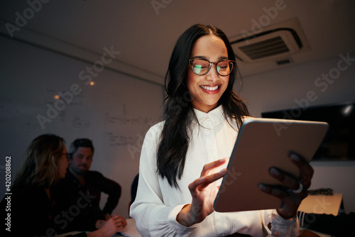 Portrait of a smiling young female team leader employee using digital tablet in office photo