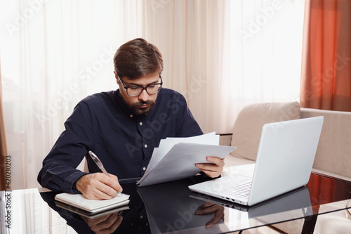 Entrepreneur works with a laptop and keeps a document in a home office