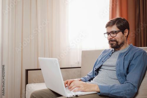 Handsome young man using laptop computer at home.