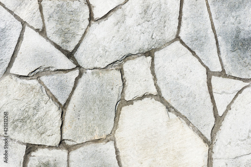 Mosaic stones construction backdrop. Grunge uneven brick wall pattern. Pieces of cracked blocks in concrete wall background. Gray concrete joint. Decorative exterior wall.