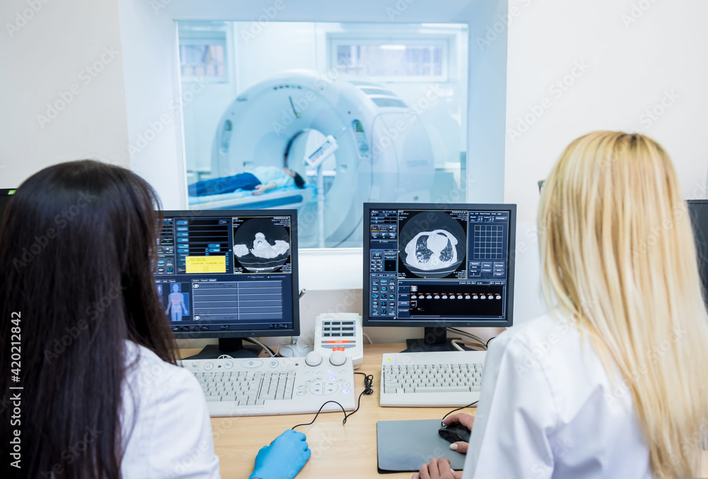 Radiologist and assistant in the control room of computed tomography at ...