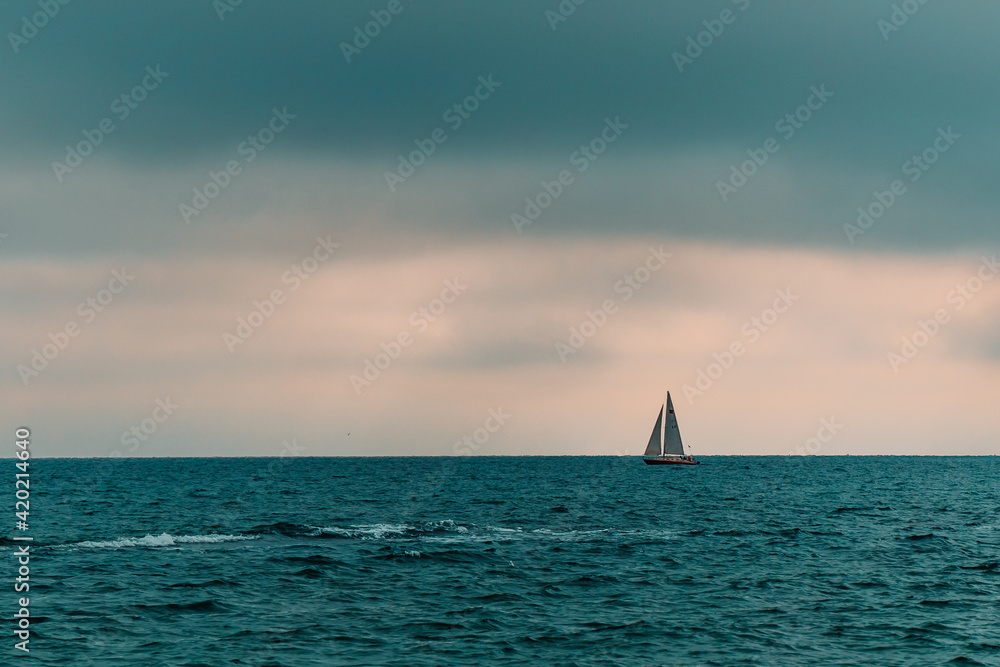 a lonely yacht goes to sea on a cloudy day. sailing on the water