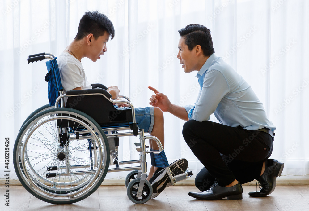Asian doctor talking, support, and encouragement to a young disabled boy in a wheelchair Asian doctor talking, support, and encouragement to a young disabled boy in a wheelchair