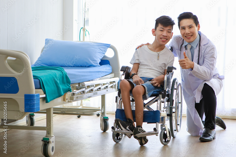 Happy and positive mind disable Asian boy on a wheelchair taking a photo with a doctor in a patient hospital room Happy and positive mind disable Asian boy on a wheelchair taking a photo with a doctor in a patient hospital room