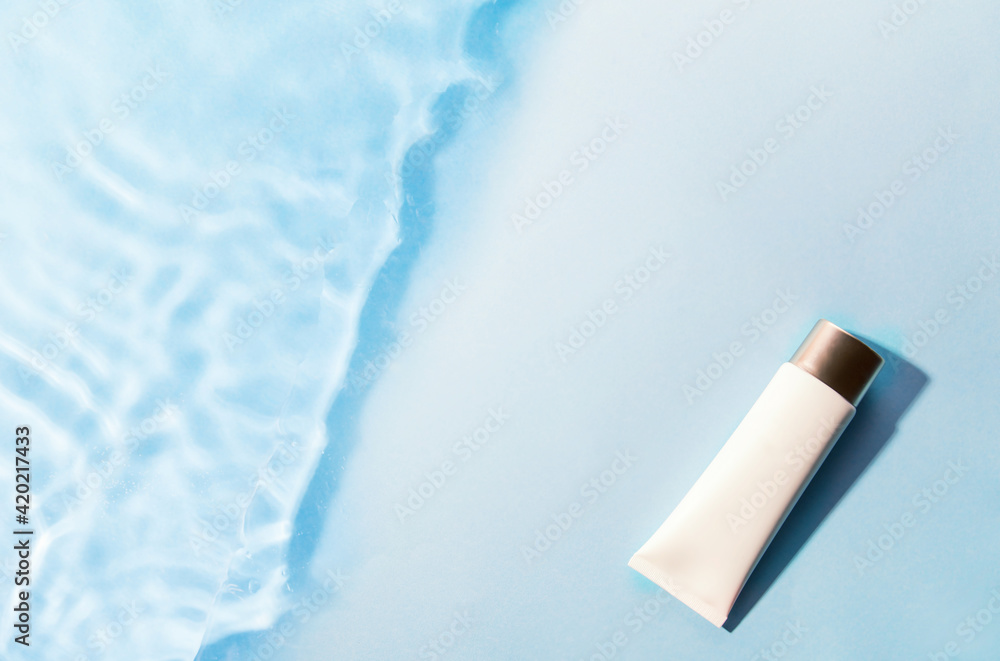 Tube of sunscreen on blue water surface. Cosmetic cream lotion, sunscreen on blue background of summer pool. Summer vacation cosmetics concept. Tube of sunscreen on blue water surface. Cosmetic cream lotion, sunscreen on blue background of summer pool. Summer vacation cosmetics concept.