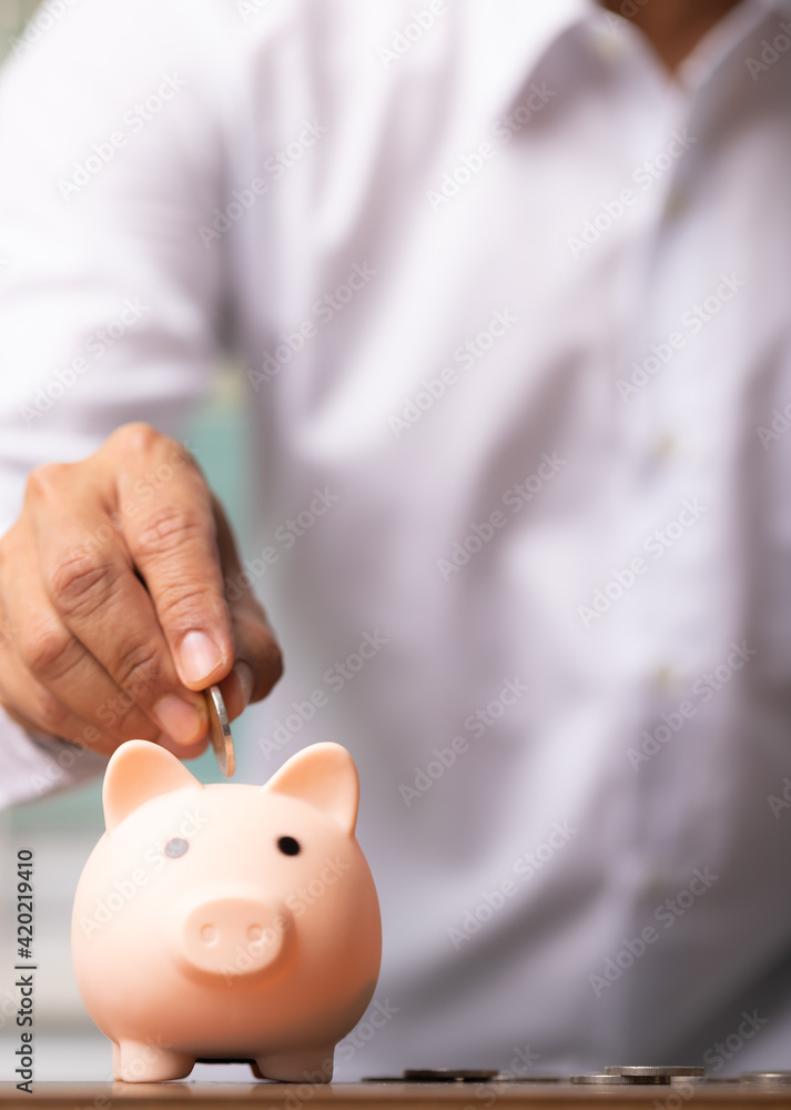 Vertical man hand putting coins into the piggy bank savings, business concept. Vertical man hand putting coins into the piggy bank savings, business concept.