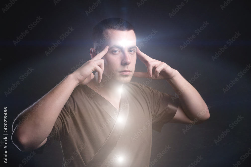 Portrait of an enlightened Caucasian male physiotherapist with glowing chakras. The telepath holds his fingers to the scales while reading your mind Portrait of an enlightened Caucasian male physiotherapist with glowing chakras. The telepath holds his fingers to the scales while reading your mind