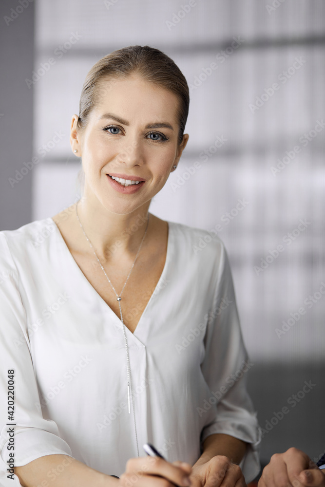 Businesswoman sitting and looking at camera in office. Business headshot