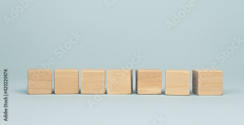 Seven blank wooden cube blocks on blue background