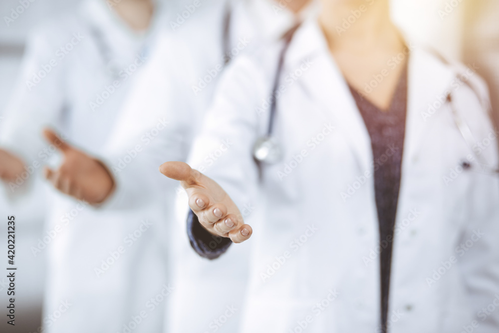 Doctors standing as a team while offering helping hand for shaking hand or saving life in sunny clinic. Medicine concept Doctors standing as a team while offering helping hand for shaking hand or saving life in sunny clinic. Medicine concept