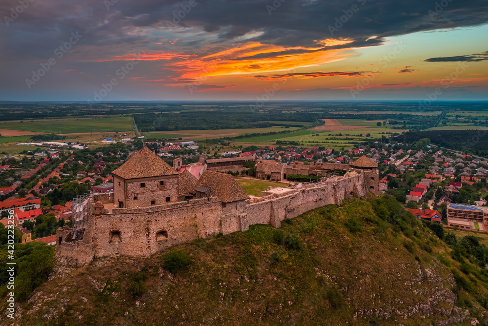 Sumeg, Hungary - Aerial panoramic view of the famous High Castle of Sumeg in Veszprem county at sunset with storm clouds and dramatic colors of sunset at background on a summer afternoon