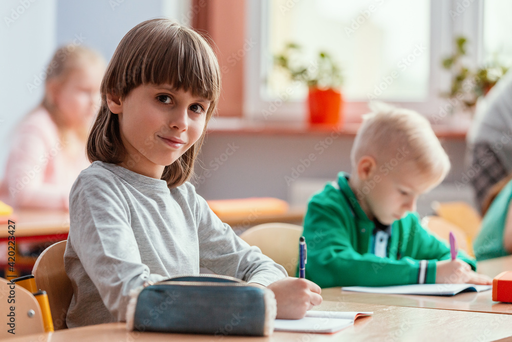 Children sit at the tables in the classroom waiting for the first lesson in the new school year Children sit at the tables in the classroom waiting for the first lesson in the new school year