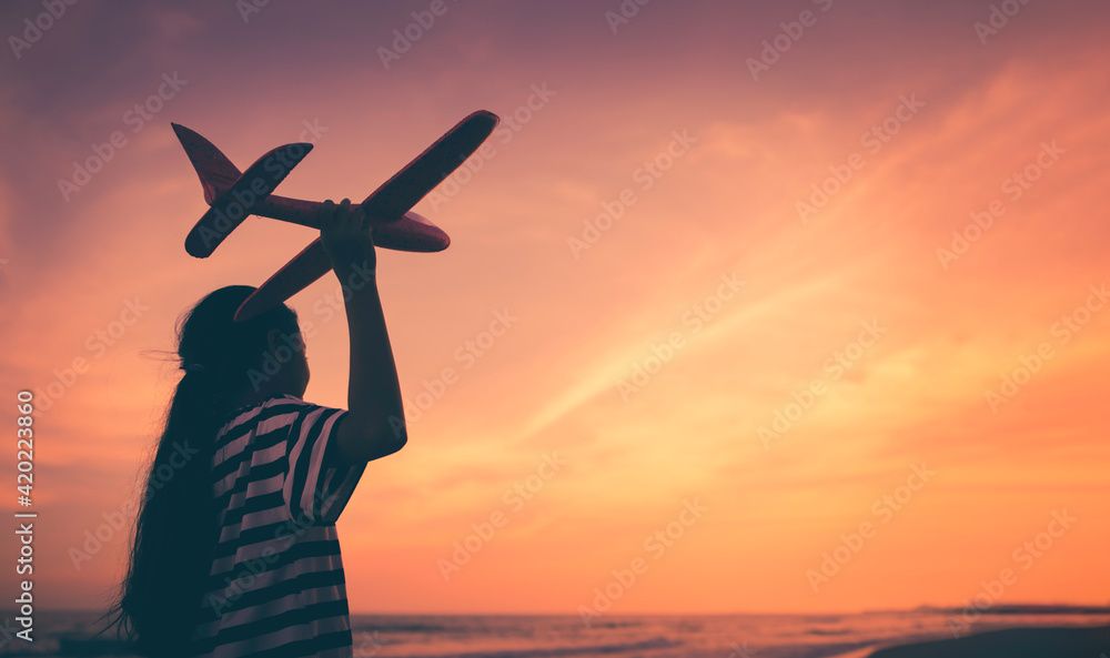 Fototapeta premium Silhouette asian girl playing aeroplane on the beach, Hopeful or future challenge concept
