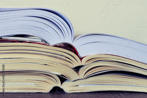 Closeup of a pile of open books on a table. School, College, University concept. Copy space.