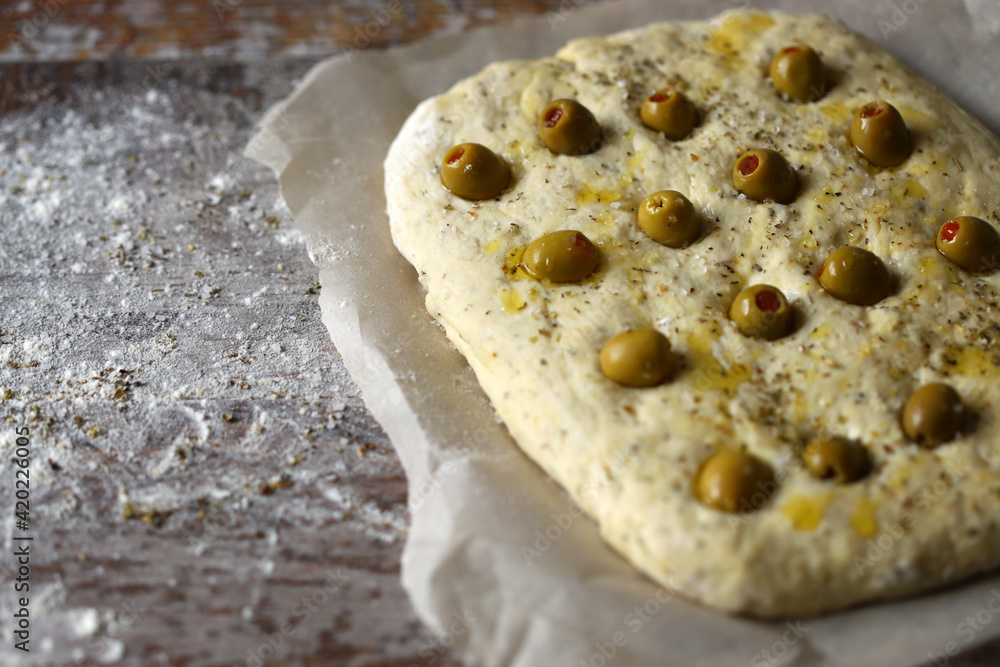 Italian focaccia with olives before baking. Raw ciabatta. Cooking focaccia with olives.