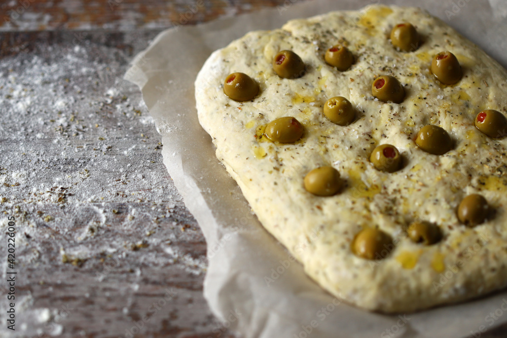 Italian focaccia with olives before baking. Raw ciabatta. Cooking focaccia with olives. Italian focaccia with olives before baking. Raw ciabatta. Cooking focaccia with olives.