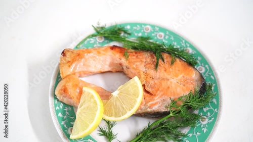 Cooking video. Juicy and appetizing red fish lies on a festive white plate. Green dill, parsley. Smooth camera movement around the dish. Video good for restaurant, cafe menu, fresh food house delivery